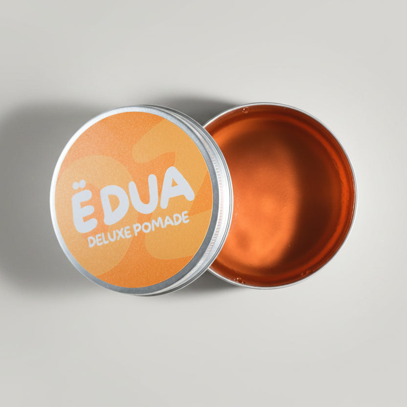 Open container of ÉDUA Deluxe Pomade with visible pomade inside on a light gray background